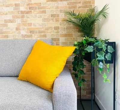 a yellow pillow on a couch next to a brick wall at Tarongers, lovely flat in the center in Valencia