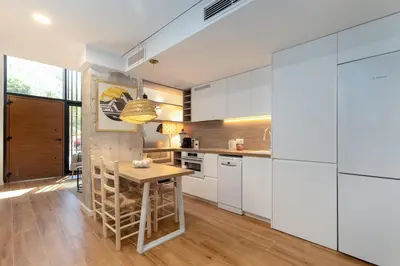 a kitchen with white cabinets and a wooden table at ApartUP Opera Loft Love in Valencia