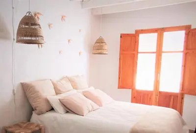 a bedroom with a bed with white sheets and a window at Casa El Olmo de Navajas in Navajas
