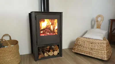 a fireplace in a living room next to a basket at Casa El Olmo de Navajas in Navajas