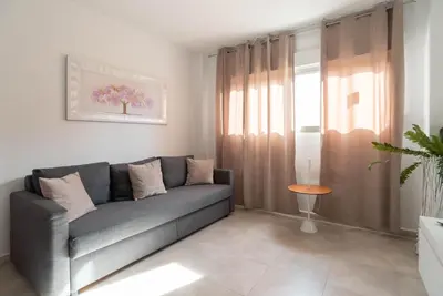 a living room with a gray couch and a window at Magnifico apartamento cerca del centro con A.A. - CID 2 in Burriana