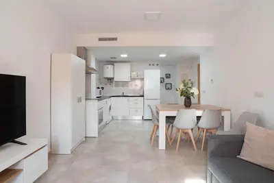 a kitchen and living room with a table and a couch at Magnifico apartamento cerca del centro con A.A. - CID 2 in Burriana