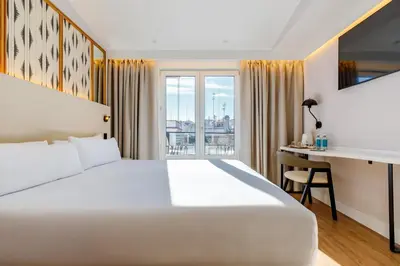 a hotel room with a bed and a desk and a window at Petit Palace Plaza de la Reina in Valencia