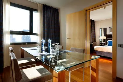 a room with a glass table with chairs and a bedroom at Eurostars Gran Valencia in Valencia