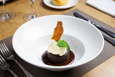 a white bowl of chocolate dessert with whipped cream and mint at Eurostars Acteón in Valencia