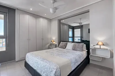 a bedroom with a large bed and two windows at Ático frente al mar, PataconaBlue, complejo vacacional in Valencia
