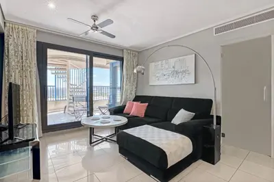 a living room with a couch and a table at Ático frente al mar, PataconaBlue, complejo vacacional in Valencia