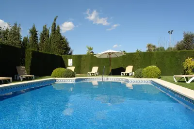 a swimming pool in a yard with chairs and an umbrella at Ad Hoc Parque in Bétera