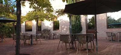 an outdoor patio with tables and chairs and an umbrella at Ad Hoc Parque in Bétera