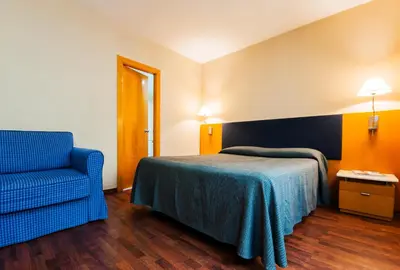 a bedroom with a bed and a blue chair at Hotel Villacarlos in Valencia