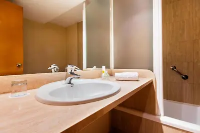a bathroom with a sink and a mirror and a tub at Hotel Villacarlos in Valencia