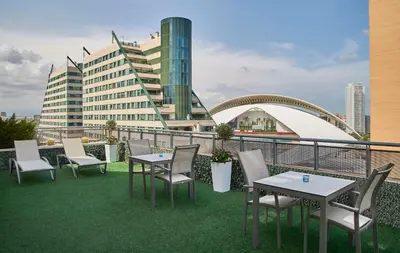 a balcony with tables and chairs and a building at NH Valencia Las Artes in Valencia