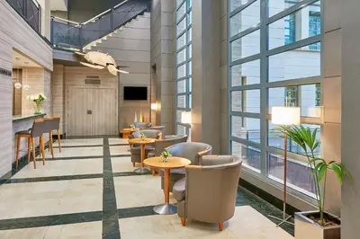 a lobby with tables and chairs and windows at NH Valencia Las Artes in Valencia