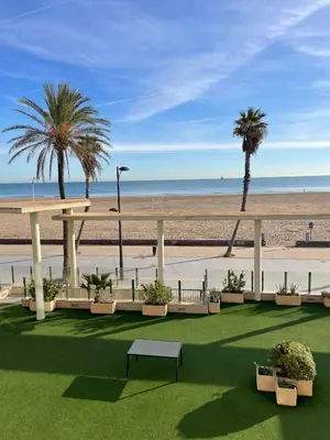 a view of a beach with palm trees and a table at PRIMERA LINEA PLAYA PATACONA, VALENCIA in Valencia
