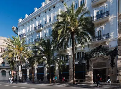 a large white building with palm trees in front of it at One Shot Reina Victoria in Valencia