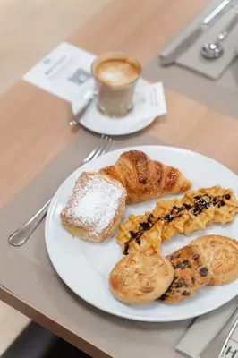a plate of pastries and a cup of coffee on a table at Hotel RH Sorolla Centro in Valencia