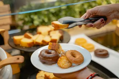 a person holding a plate of donuts and bread at Hotel RH Sorolla Centro in Valencia
