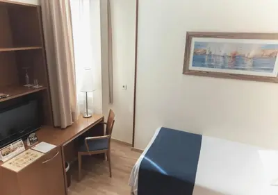 a hotel room with a bed and a desk with a television at Hotel RH Sorolla Centro in Valencia