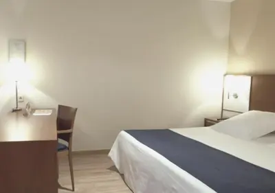 a bedroom with a bed and a desk and a chair at Hotel RH Sorolla Centro in Valencia