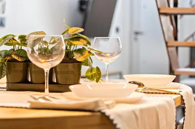 two wine glasses and plates on a table with a plant at Loft Nou Benicalap - Housevanlive in Valencia