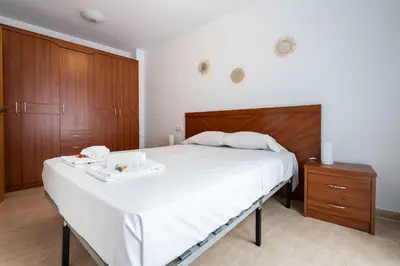 a bedroom with a large white bed with wooden cabinets at Excelente apartamento en 2ª línea de playa by Hometels in Puerto de Sagunto