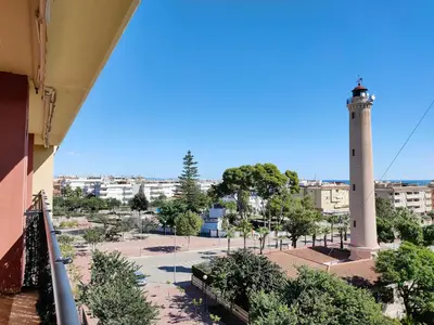 a lighthouse in the middle of a city with a street at Global Vacacional, Apartamento con gran terraza y piscina in Canet de Berenguer