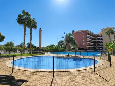 a swimming pool in a park with palm trees at Global Vacacional, Apartamento con gran terraza y piscina in Canet de Berenguer