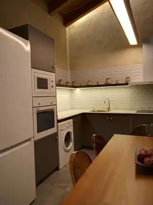 a kitchen with a table and a white refrigerator at Casa rural El Forn d'Alcudia de Veo in Alcudia de Veo