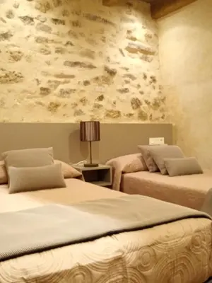 a bedroom with two beds and a stone wall at Casa rural El Forn d'Alcudia de Veo in Alcudia de Veo