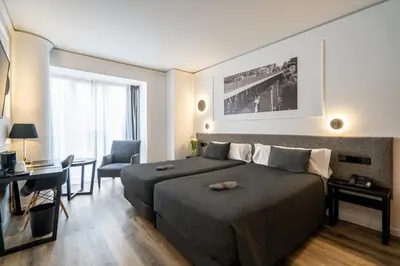 a bedroom with a bed and a desk and a chair at Hotel Conqueridor in Valencia