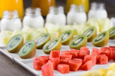 a plate of fruit on a table with kiwis and watermelon at AC Hotel Valencia by Marriott in Valencia