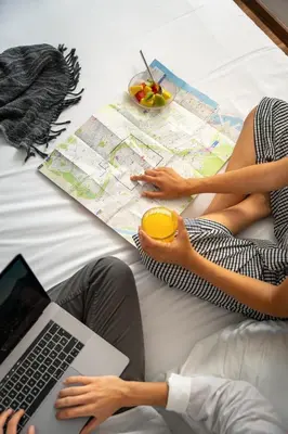 two people sitting on a bed with a map and a laptop at Hotel Kramer in Valencia