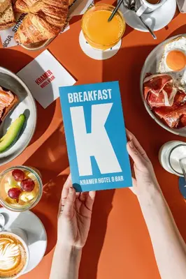 a person holding up a breakfast k book over a table at Hotel Kramer in Valencia