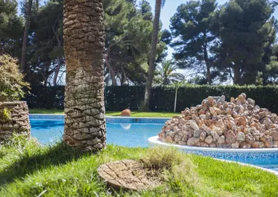 a large pile of rocks sitting next to a palm tree at Apartamento Florazar 2, 10ºC Cullera in Faro de Cullera