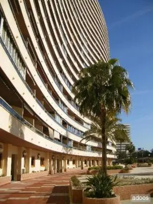 a large building with a palm tree in front of it at Apartamento Florazar 2, 10ºC Cullera in Faro de Cullera
