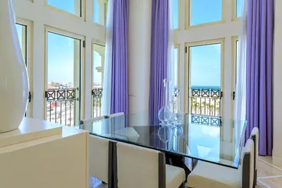 a dining room with a glass table and purple curtains at Las Arenas Balneario Resort in Valencia