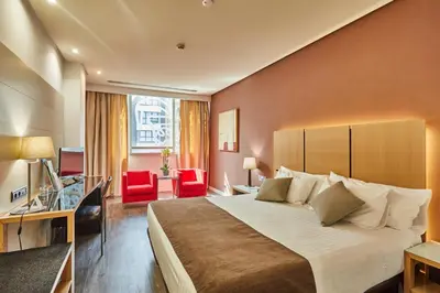 a hotel room with a large bed and red chairs at Silken Puerta Valencia in Valencia