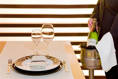 a person standing next to a table with two glasses of wine at Silken Puerta Valencia in Valencia