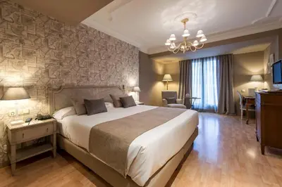 a bedroom with a large bed and a chandelier at Vincci Lys in Valencia