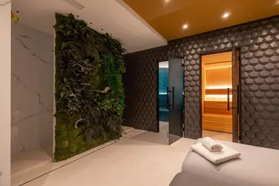 a bathroom with a green wall with a couch and a shower at Hotel Neptuno Playa & Spa in Valencia