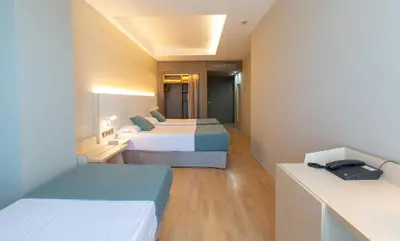 a hotel room with two beds and a desk at Hotel Olympia Valencia in Alboraya