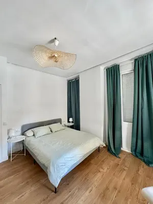 a bedroom with a bed with green curtains and a chandelier at Vlc Center 4 Room Apartment in Valencia