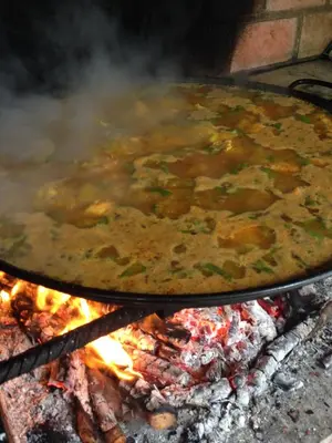 a pot of food is cooking on a grill at El Oasis Villa Resort in La Eliana