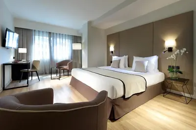 a hotel room with a large bed and a chair at Exe Rey Don Jaime in Valencia