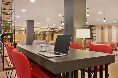 a laptop computer sitting on a table with red chairs at Ramada by Wyndham Valencia Almussafes in Almussafes