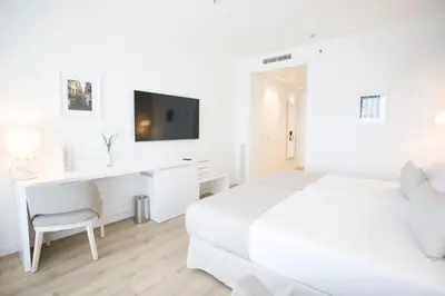 a white bedroom with a white bed and a desk at Hotel Albufera in Alfafar