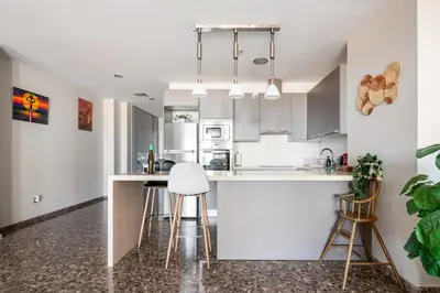 a kitchen with white cabinets and bar stools at Moderno apartamento con vistas al mar en Valencia in Valencia