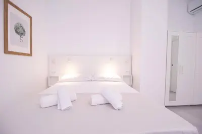 a white bedroom with a large white bed with white pillows at Viveros by Concept Flats in Valencia