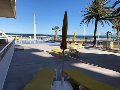 a patio with chairs and umbrellas and the beach at Florazar 3 in Cullera