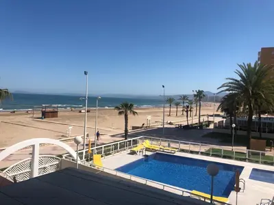 a swimming pool next to a beach with palm trees at Florazar 3 in Cullera